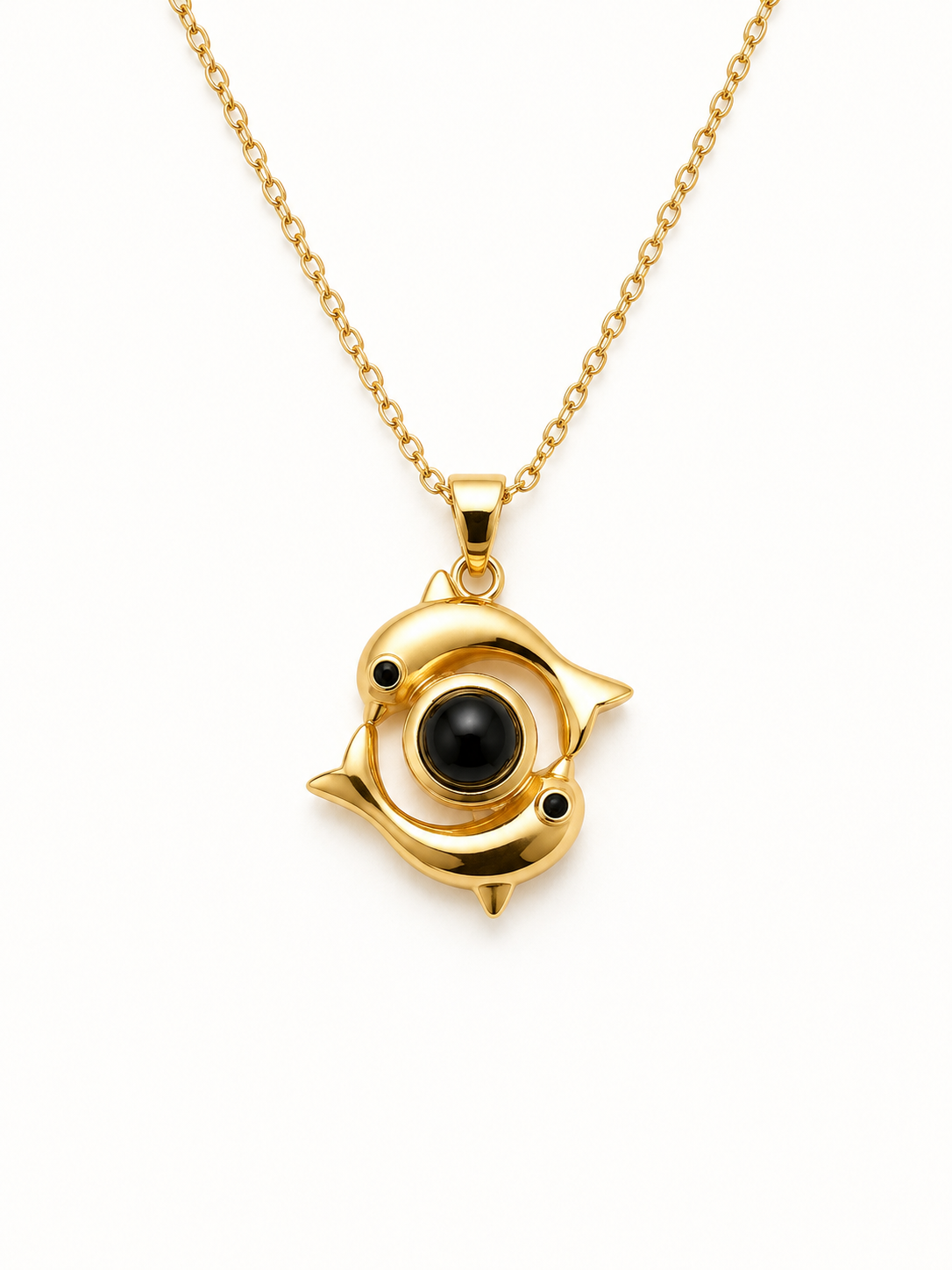 A gold pendant necklace featuring a stylized fish design with a central black circular stone and small black accents, suspended from a gold chain on a white background.