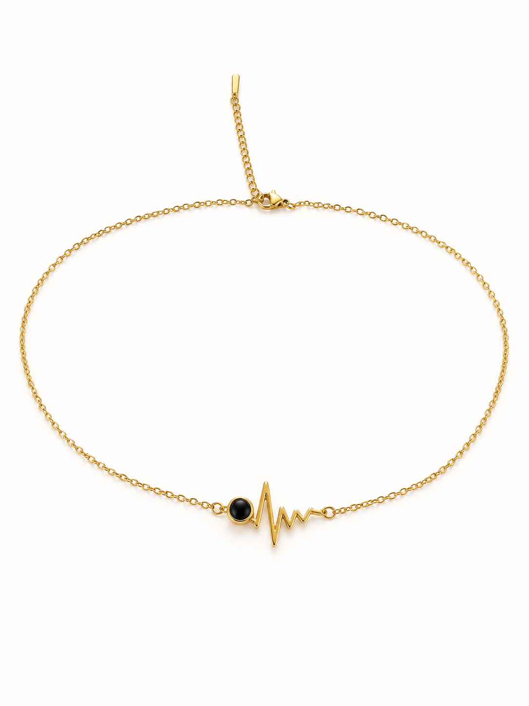A delicate gold chain necklace featuring a central gold heartbeat EKG line charm with a small black oval stone accent, displayed on a clean white background.