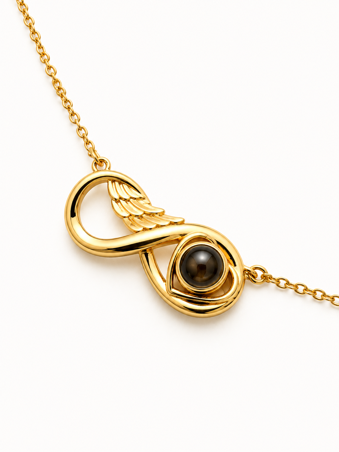 A gold infinity-shaped pendant necklace featuring a small wing detail and a dark brown tiger's eye bead in the center, shown on a clean white background.
