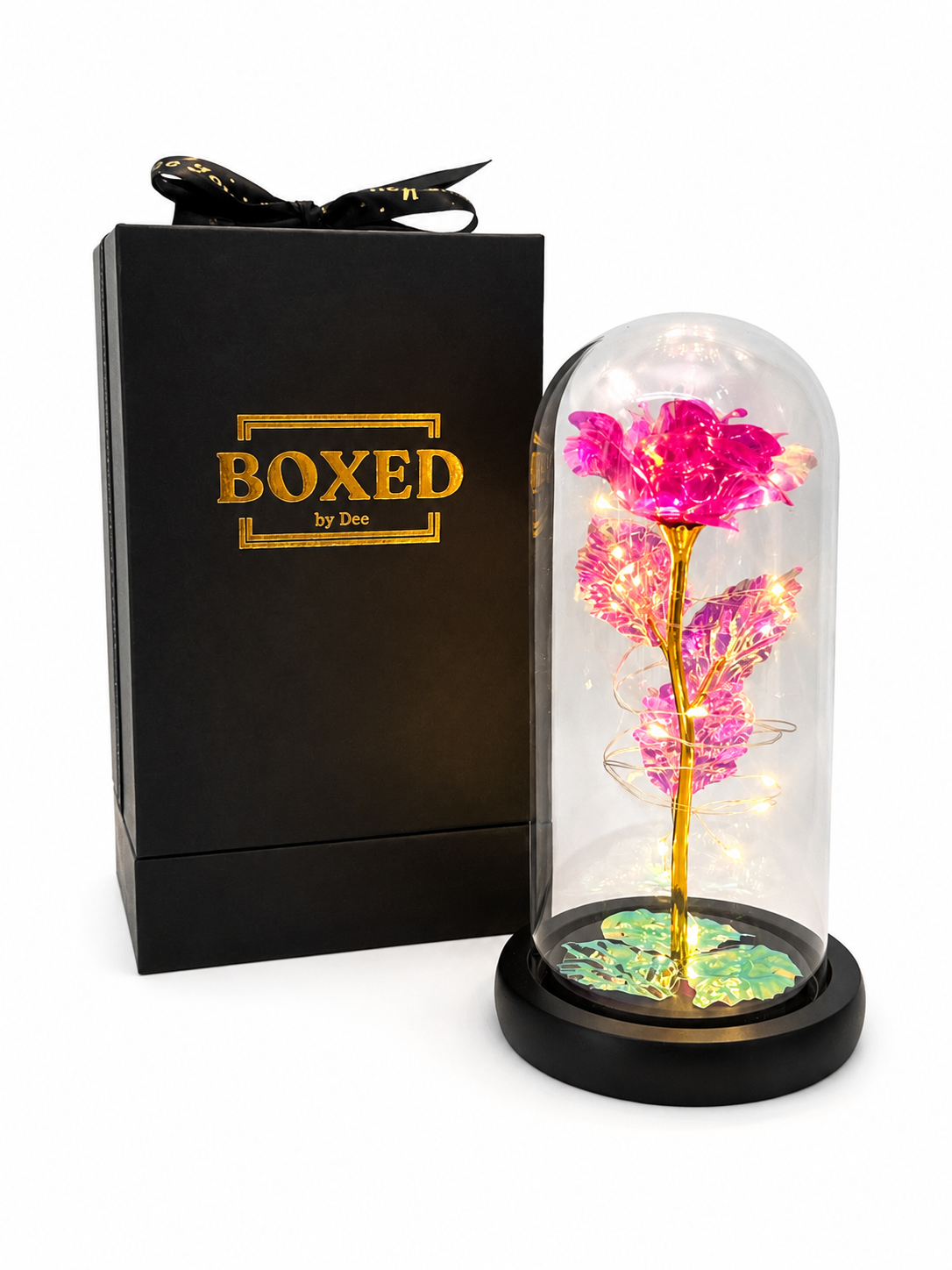 A Pink metallic rose displayed under an illuminated glass dome and presented beside a beautiful Boxed by Dee gift box with a white background.
