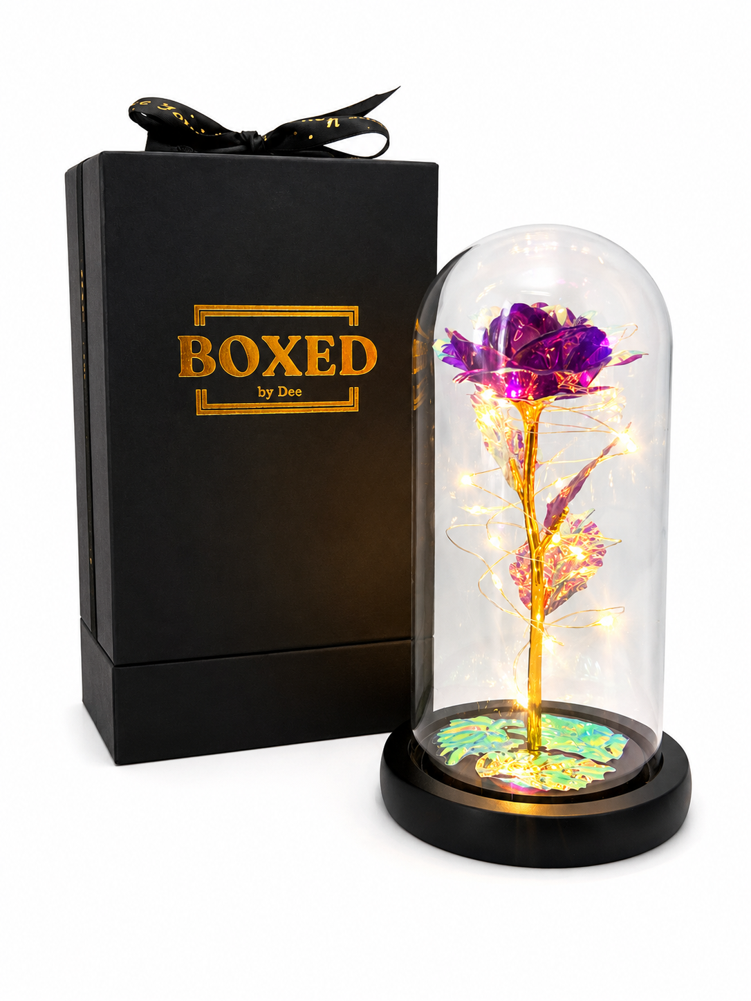 A Purple hand-made metallic rose displayed under an illuminated glass dome and presented beside a beautiful Boxed by Dee gift box with a white background.