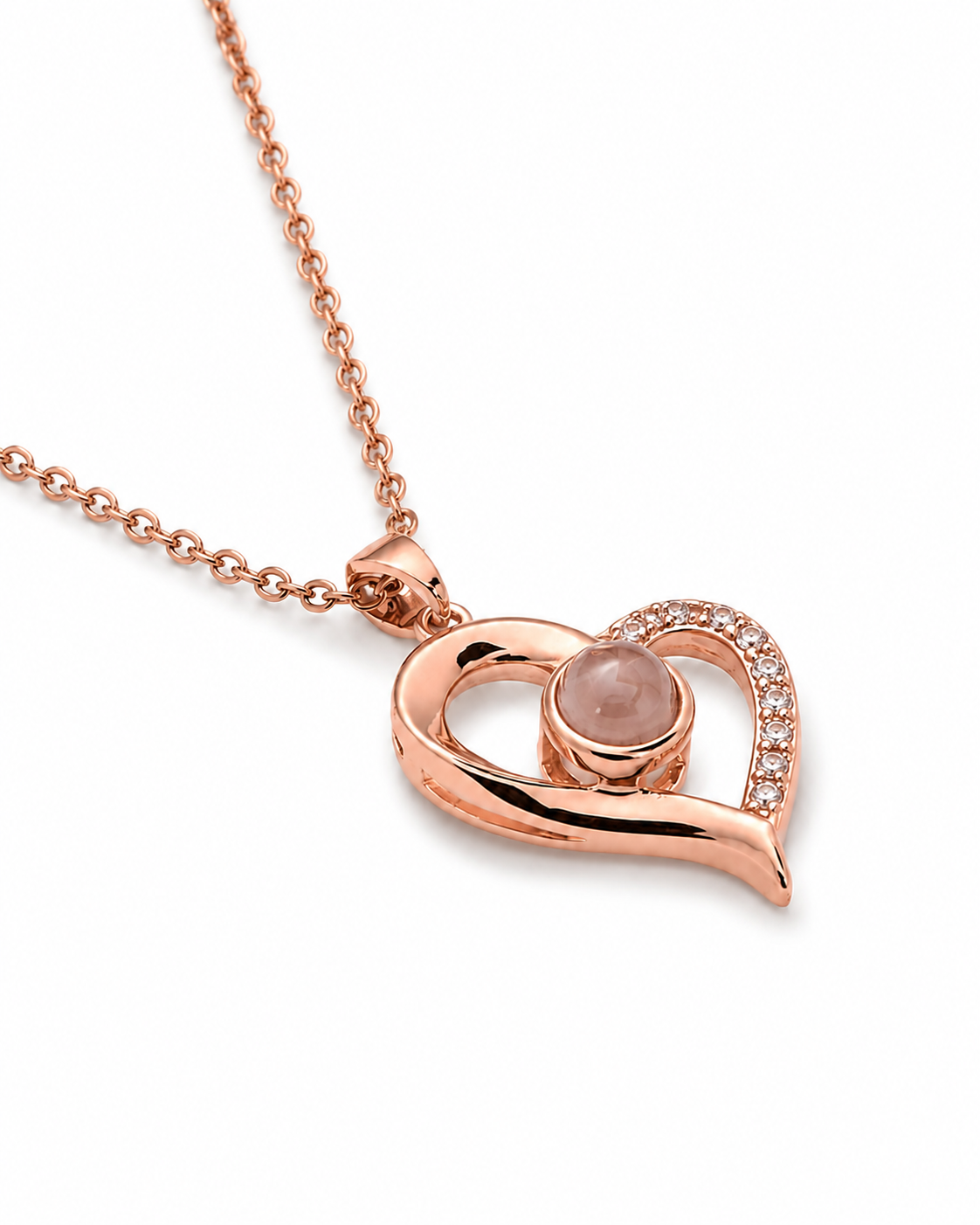 Rose gold heart pendant necklace with a central round pale pink stone and a curved row of small clear stones on one side, shown on a white background.