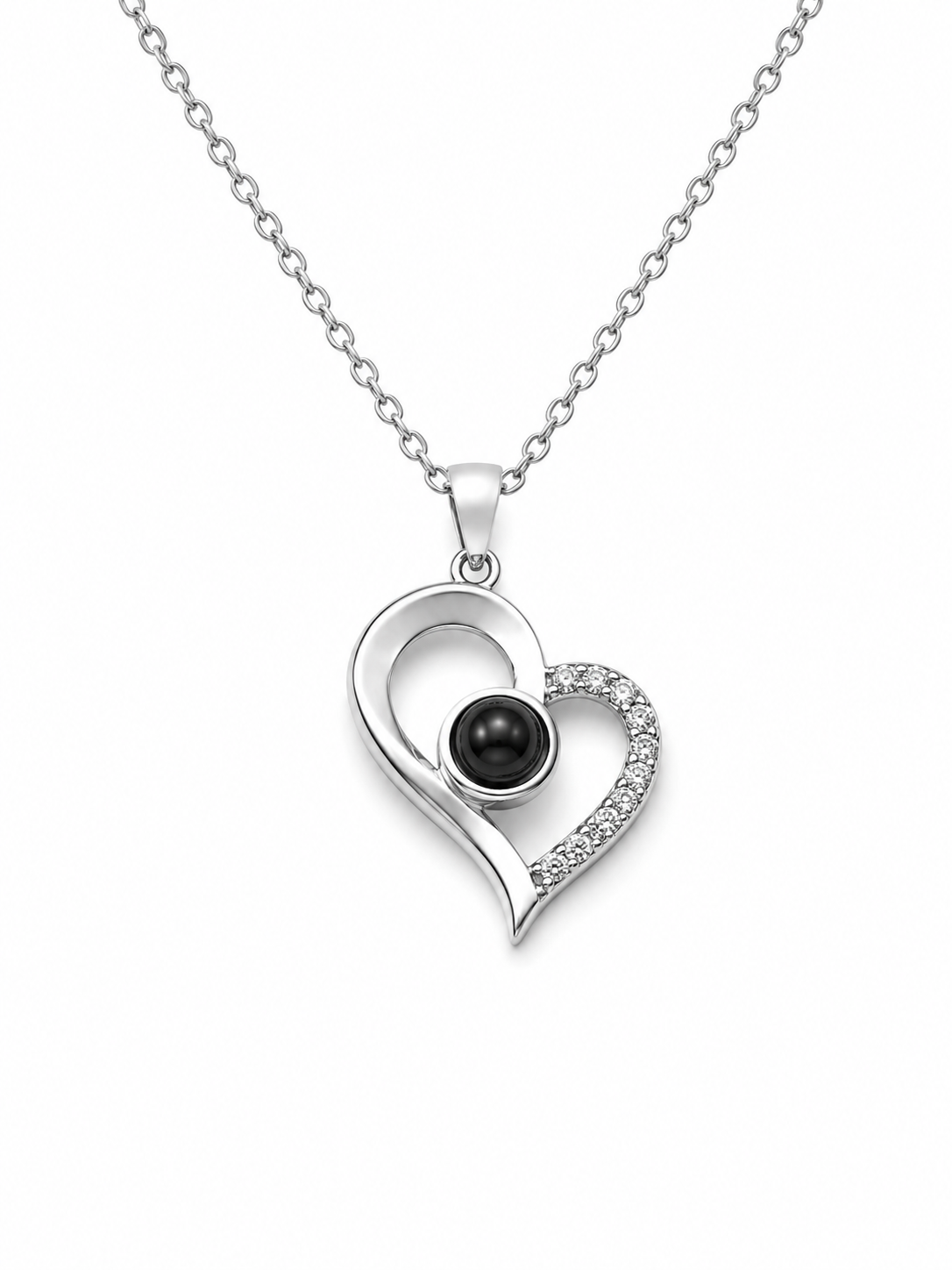 A silver heart pendant necklace featuring a polished silver heart outline with a small black pearl in the center and a pavé-set row of clear stones along the right side, suspended from a delicate silver chain against a plain white background.