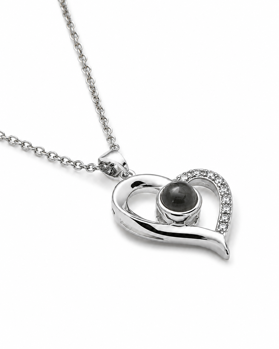 A silver heart-shaped pendant necklace featuring a central dark gray stone and a curved halo of small clear crystals, shown on a white background.