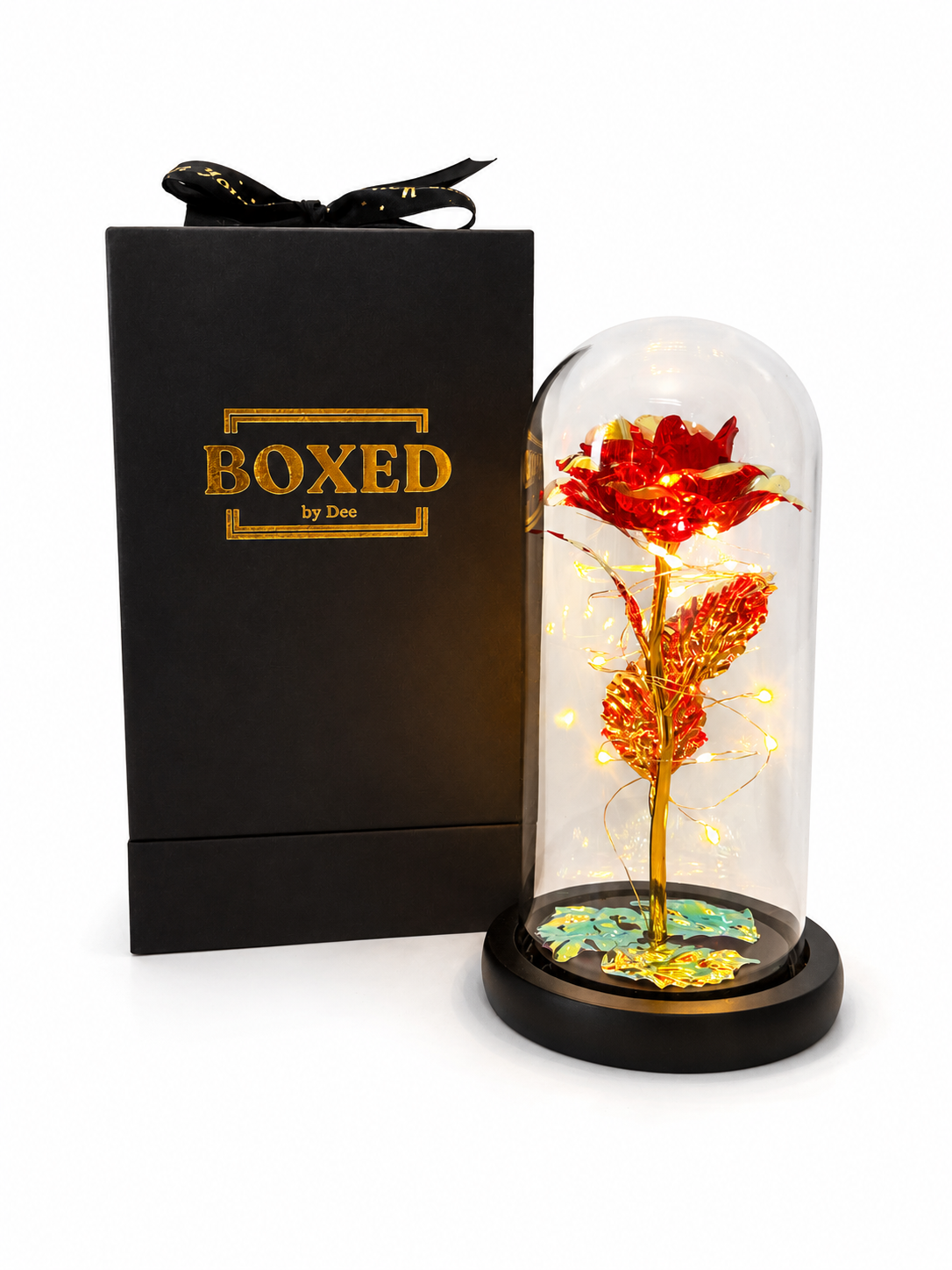 A red metallic rose displayed under an illuminated glass dome and presented beside a beautiful Boxed by Dee gift box with a white background.